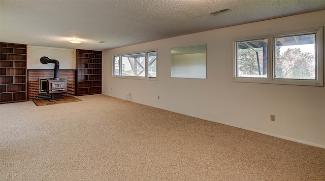 unfurnished living room with a wood stove, a textured ceiling, and carpet