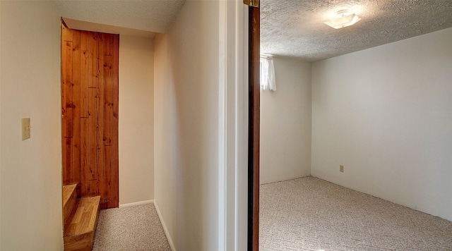 corridor featuring light carpet and a textured ceiling