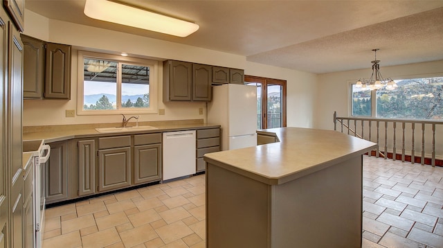 kitchen with hanging light fixtures, sink, a center island, an inviting chandelier, and white appliances