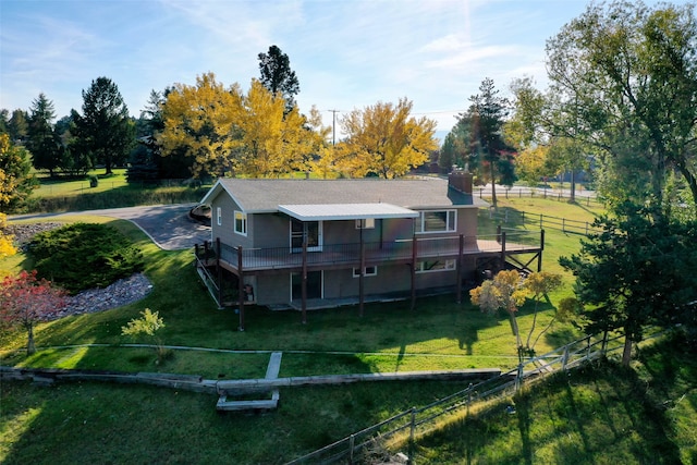 back of property with a deck and a lawn