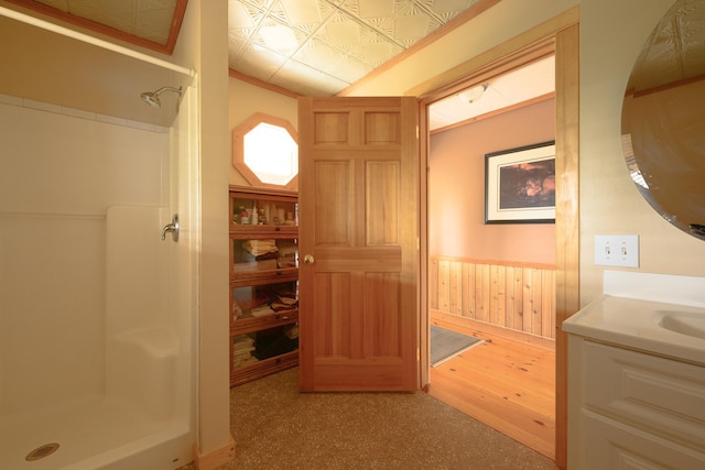 bathroom with a shower, vanity, crown molding, and wooden walls