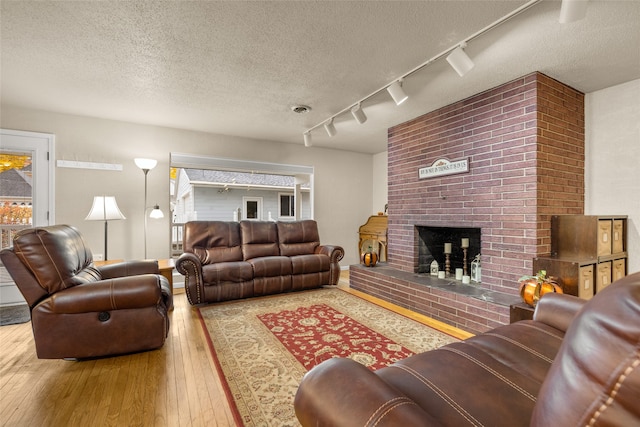 living room with a textured ceiling, track lighting, a fireplace, and hardwood / wood-style flooring