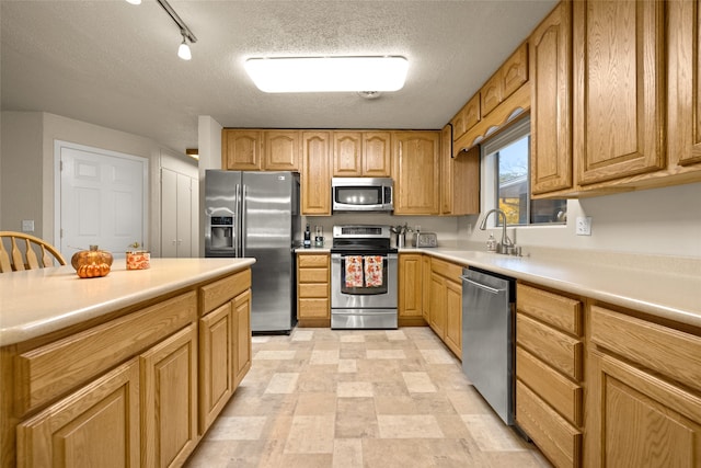 kitchen featuring a textured ceiling, sink, track lighting, and stainless steel appliances