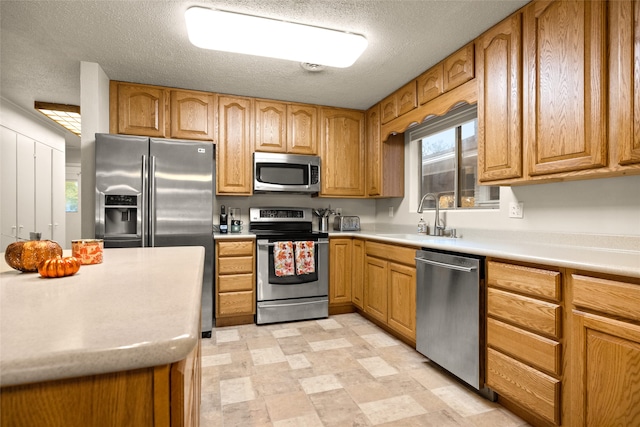 kitchen with a textured ceiling, sink, and appliances with stainless steel finishes