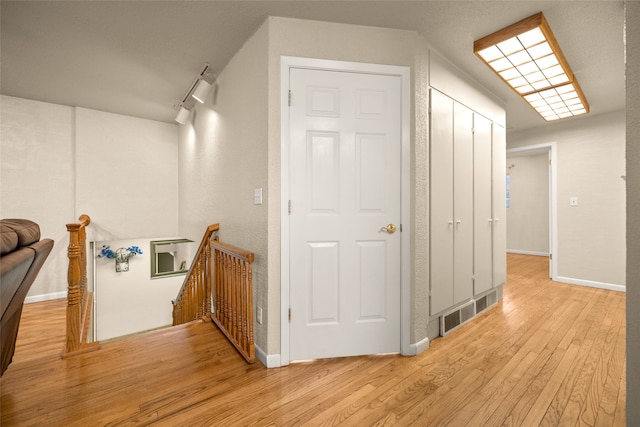 hall with light hardwood / wood-style floors and rail lighting