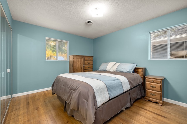 bedroom with a textured ceiling and light hardwood / wood-style flooring