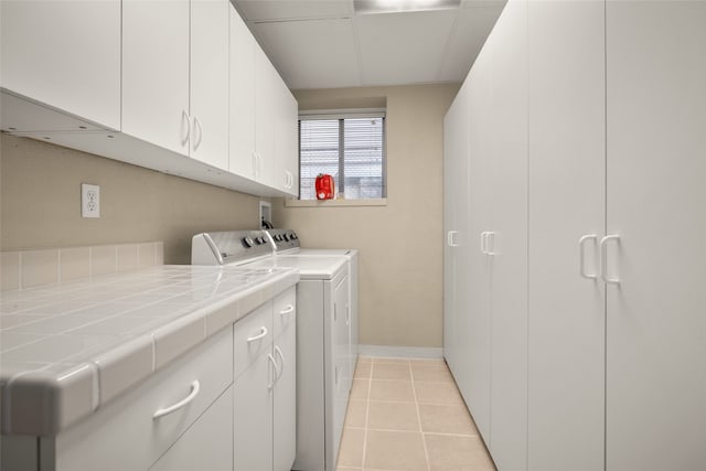 laundry room with washer and clothes dryer, cabinets, and light tile patterned floors