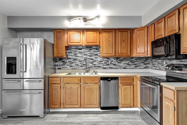 kitchen featuring sink, light hardwood / wood-style flooring, stainless steel appliances, and tasteful backsplash