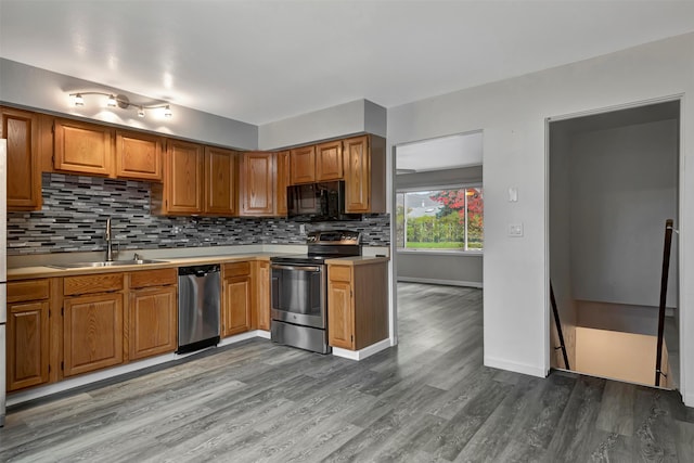 kitchen with appliances with stainless steel finishes, decorative backsplash, hardwood / wood-style flooring, and sink