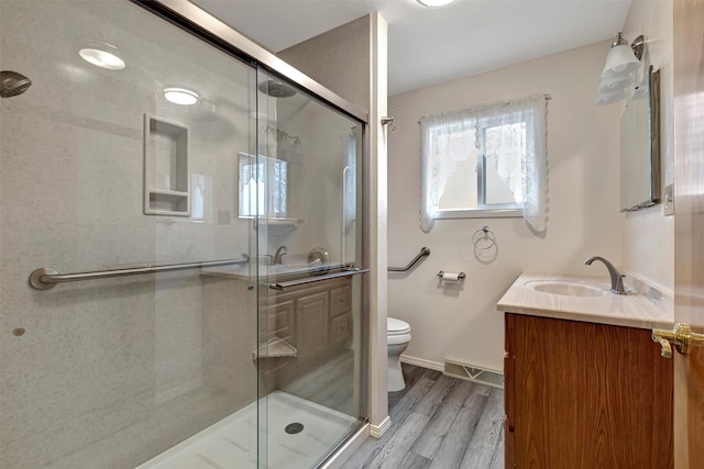 bathroom featuring vanity, toilet, wood-type flooring, and a shower with shower door