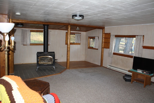 carpeted living room featuring baseboard heating and a wood stove