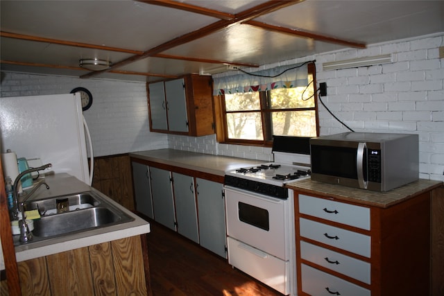 kitchen with dark hardwood / wood-style flooring, white cabinetry, sink, brick wall, and white appliances