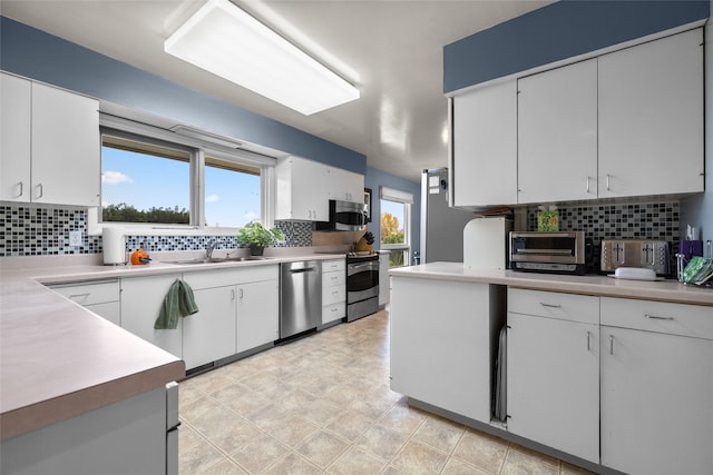 kitchen featuring sink, white cabinets, stainless steel appliances, and tasteful backsplash