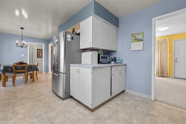 kitchen featuring light carpet, stainless steel fridge, hanging light fixtures, white cabinetry, and a notable chandelier