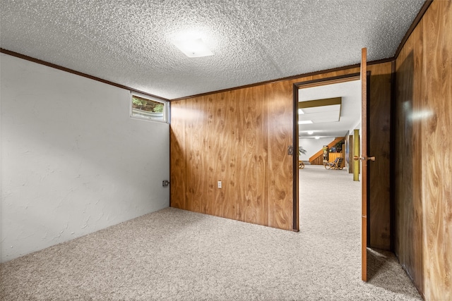 unfurnished room with ornamental molding, wood walls, a textured ceiling, and carpet floors