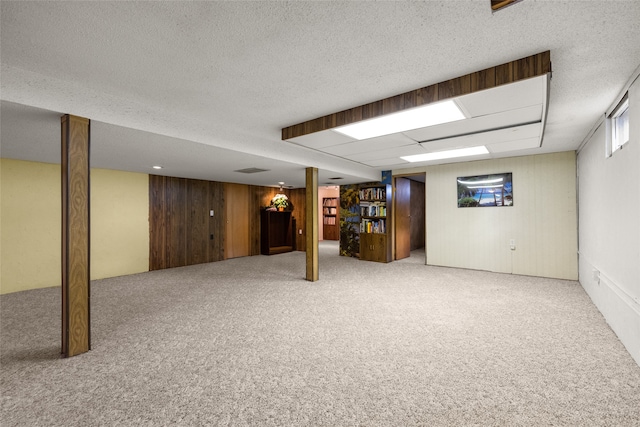 basement with a textured ceiling, wooden walls, and carpet flooring