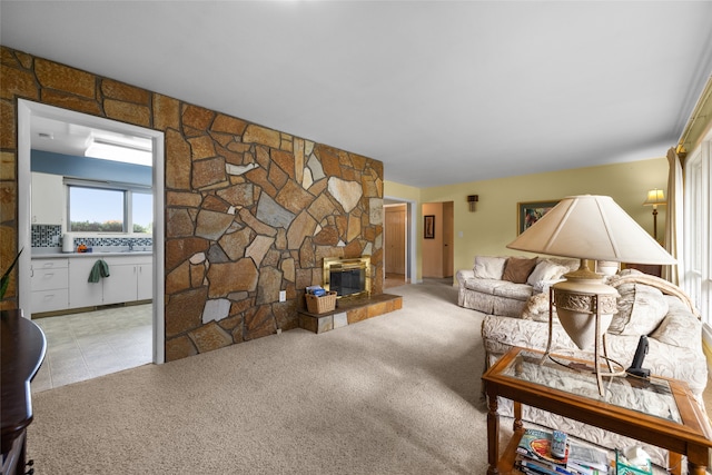 carpeted living room featuring a stone fireplace