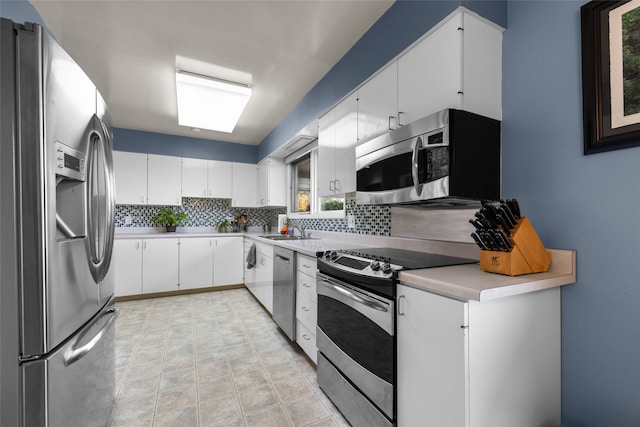 kitchen featuring backsplash, appliances with stainless steel finishes, sink, and white cabinets