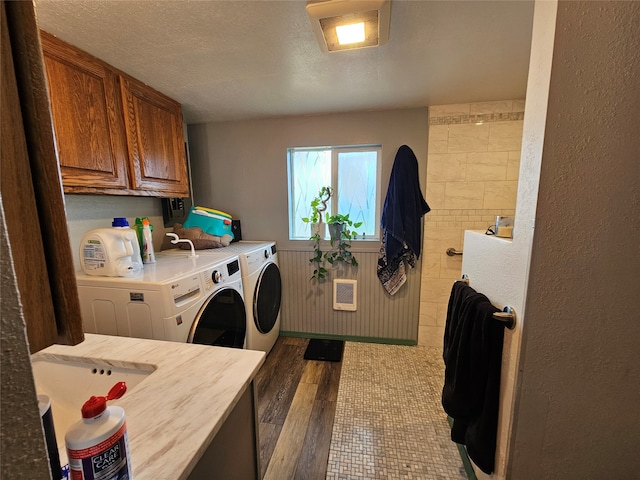 laundry area with cabinets, hardwood / wood-style floors, heating unit, washer and dryer, and a textured ceiling