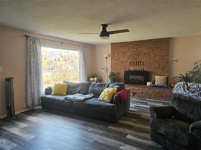 living room with dark wood-type flooring, a fireplace, a textured ceiling, and ceiling fan