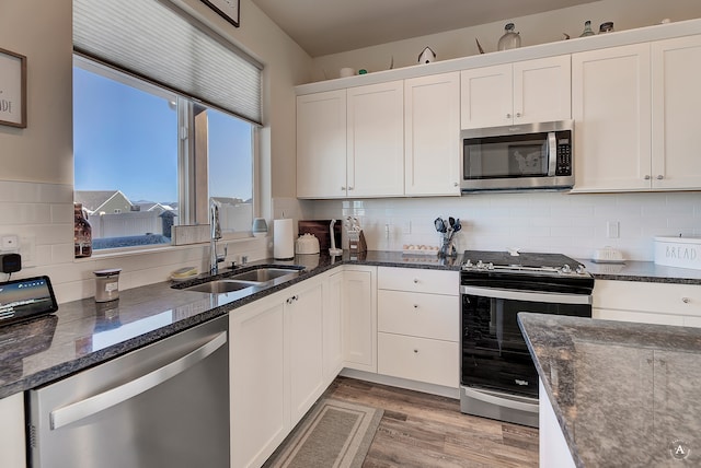 kitchen with stainless steel appliances, sink, tasteful backsplash, white cabinets, and light wood-type flooring