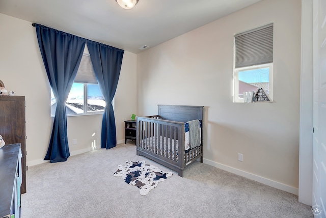 carpeted bedroom with multiple windows and a nursery area