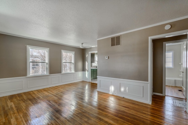 unfurnished room featuring hardwood / wood-style floors, crown molding, and a textured ceiling