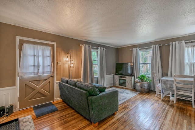 living room featuring wood-type flooring, plenty of natural light, crown molding, and a textured ceiling