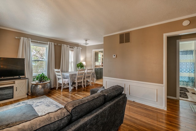 living room featuring ornamental molding, hardwood / wood-style floors, and a textured ceiling