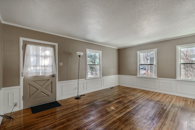 entryway with crown molding, wood-type flooring, and a textured ceiling