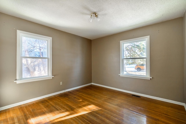 empty room featuring wood-type flooring and a textured ceiling