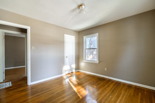 unfurnished room featuring dark hardwood / wood-style flooring and a textured ceiling