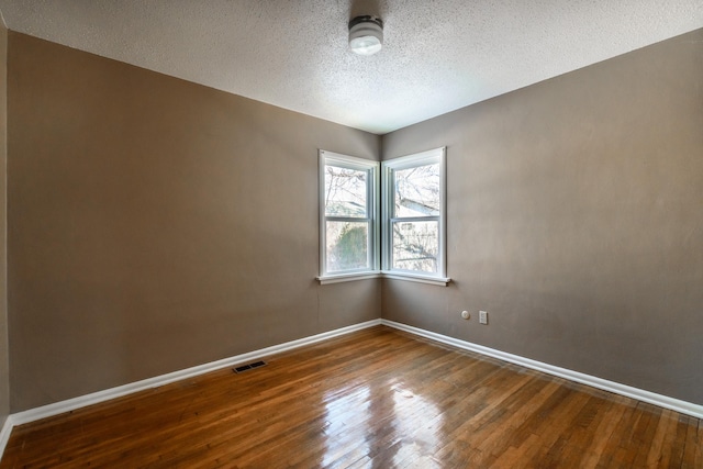 empty room with wood-type flooring and a textured ceiling