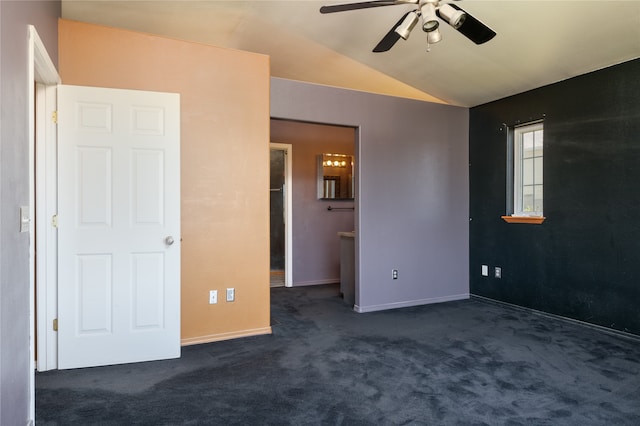 unfurnished bedroom featuring dark carpet, vaulted ceiling, a walk in closet, and ceiling fan