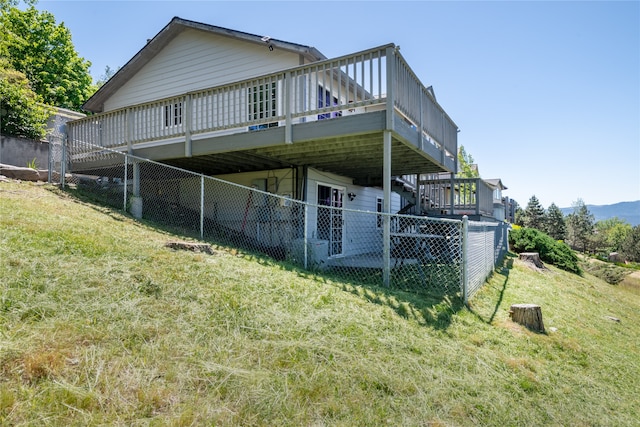 rear view of house featuring a deck and a lawn