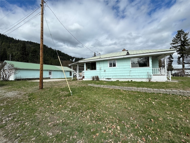 rear view of property with covered porch and a lawn