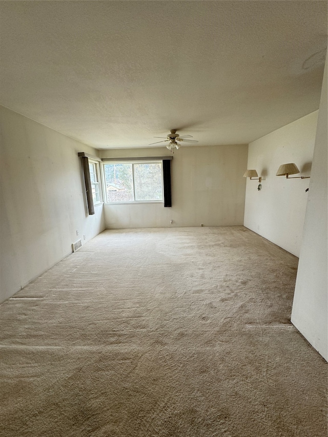 carpeted empty room with ceiling fan and a textured ceiling