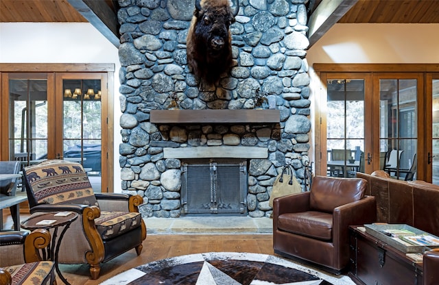 living room featuring vaulted ceiling with beams, a fireplace, french doors, wooden ceiling, and light hardwood / wood-style flooring