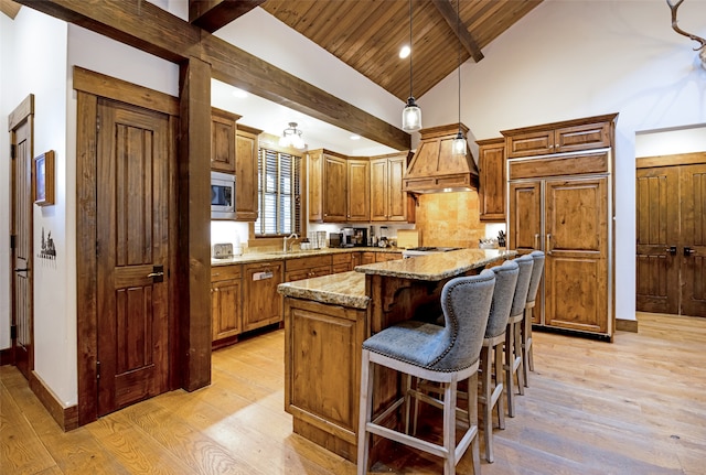 kitchen with wooden ceiling, light stone countertops, a center island, pendant lighting, and custom exhaust hood