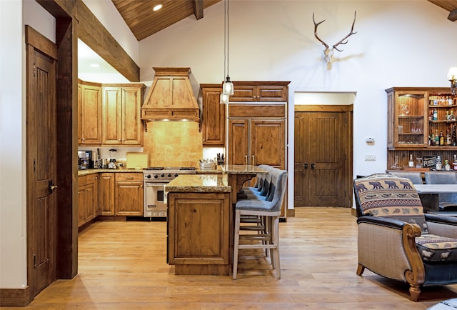 kitchen with a kitchen island, a breakfast bar area, decorative light fixtures, high end stove, and light hardwood / wood-style flooring