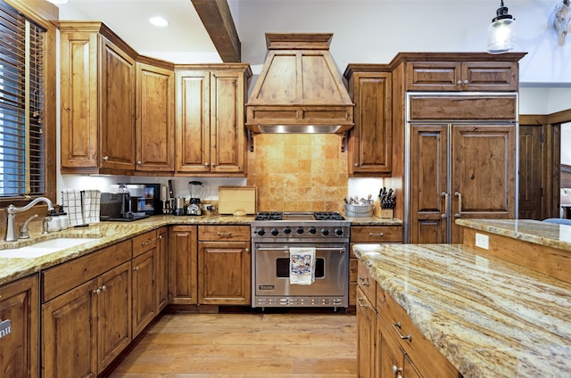 kitchen featuring designer range, light hardwood / wood-style flooring, beamed ceiling, pendant lighting, and sink