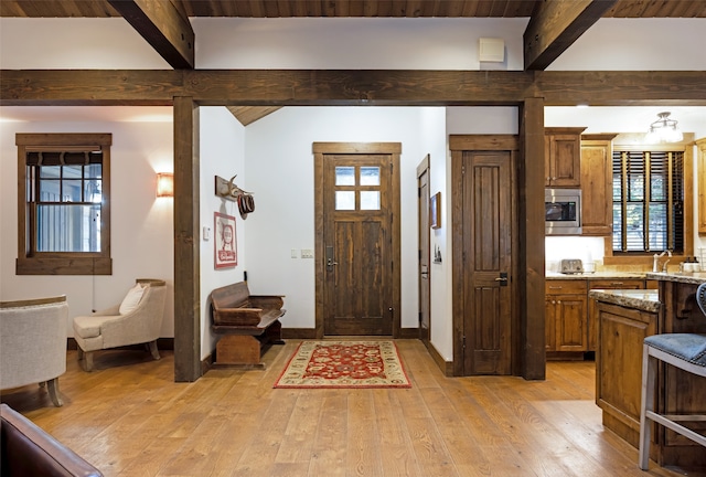 entrance foyer featuring light hardwood / wood-style floors and beam ceiling