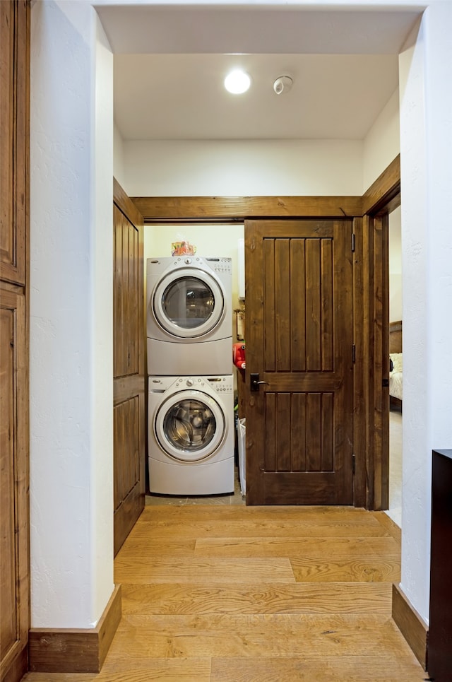 laundry room featuring stacked washer / drying machine and light hardwood / wood-style floors