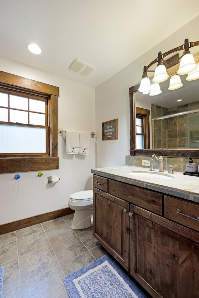 bathroom featuring vanity, toilet, and a shower with door