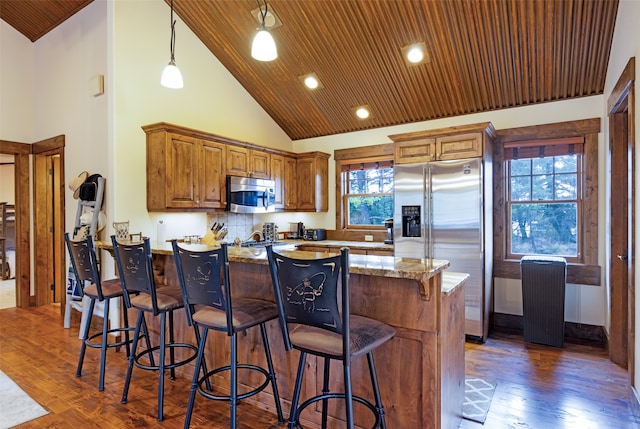 kitchen featuring wood ceiling, dark hardwood / wood-style floors, stainless steel appliances, pendant lighting, and light stone counters