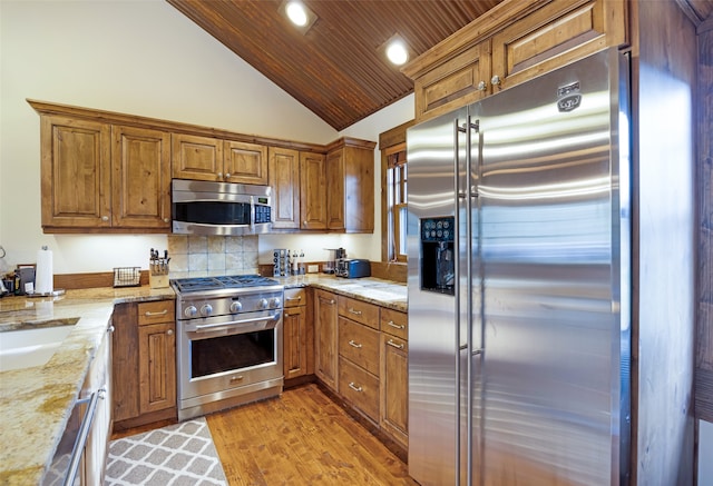 kitchen with lofted ceiling, wooden ceiling, light wood-type flooring, high quality appliances, and light stone counters