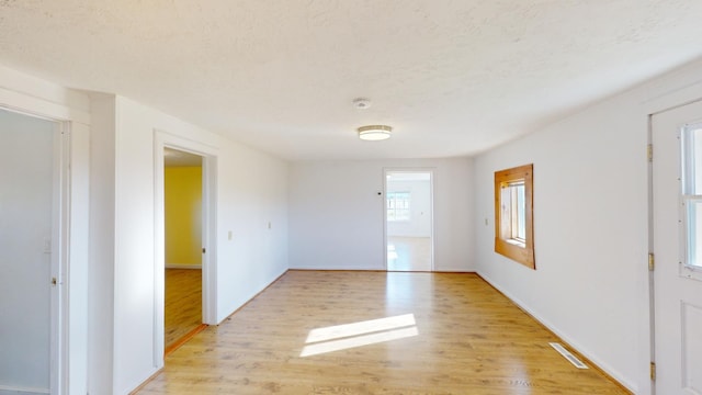 unfurnished room with light hardwood / wood-style flooring and a textured ceiling