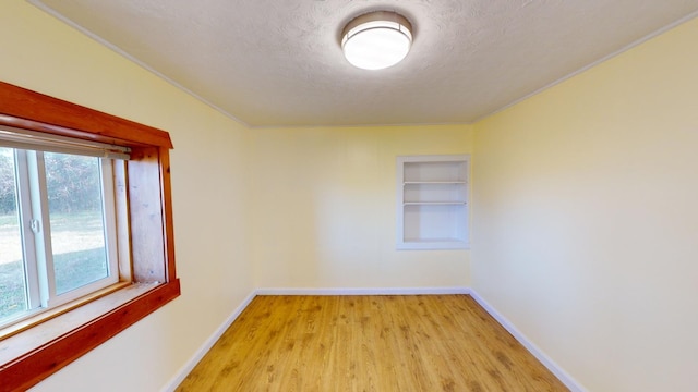 spare room with light hardwood / wood-style floors, a textured ceiling, and ornamental molding