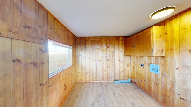 empty room with wooden walls and light wood-type flooring