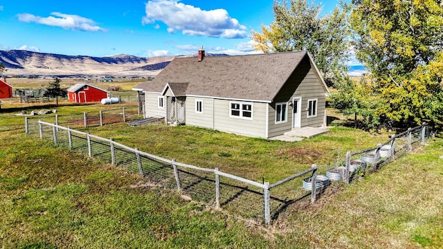 exterior space with a rural view, an outdoor structure, a yard, and a mountain view